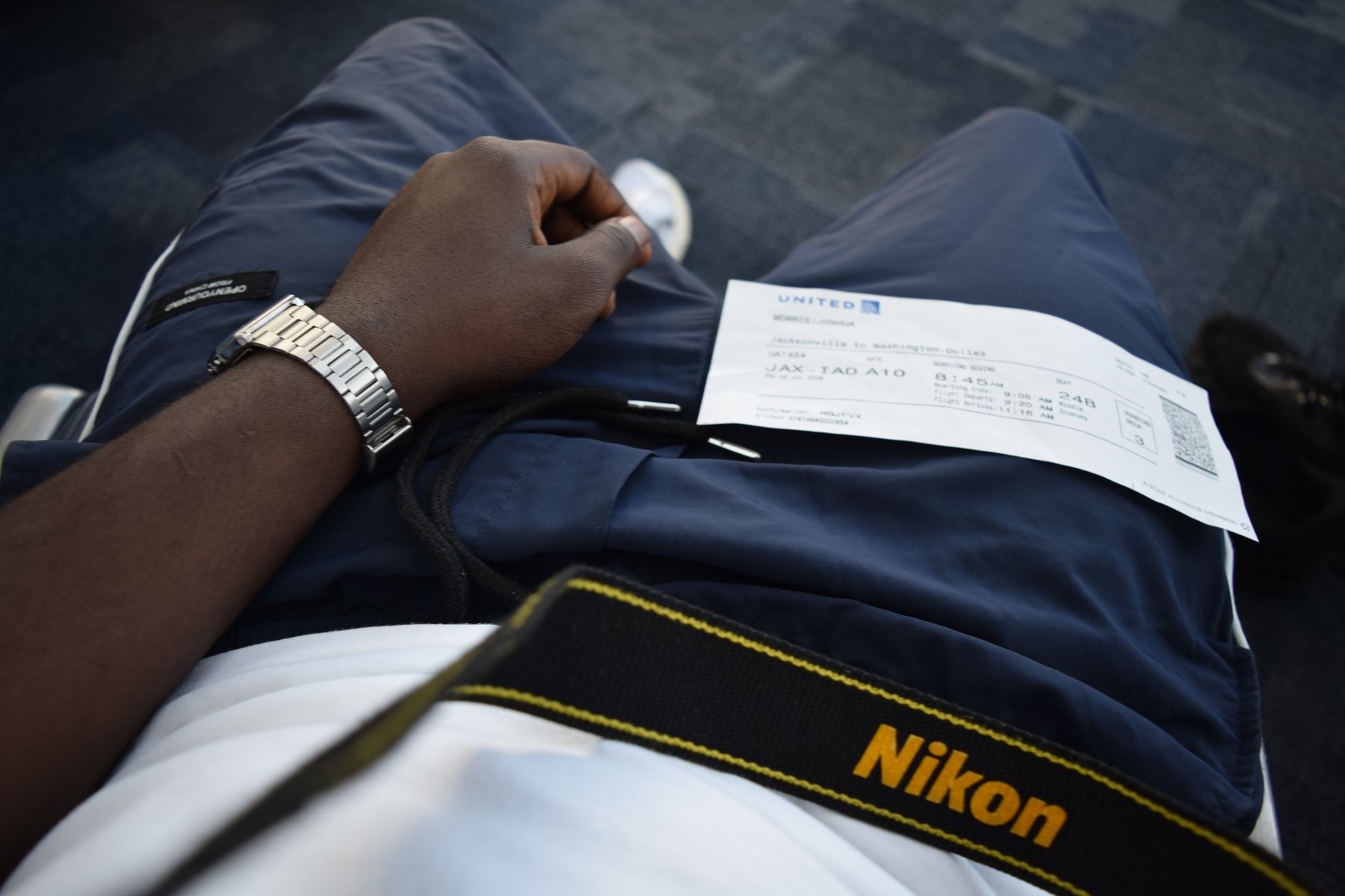 Boarding pass beside a Nikon camera strap while traveling