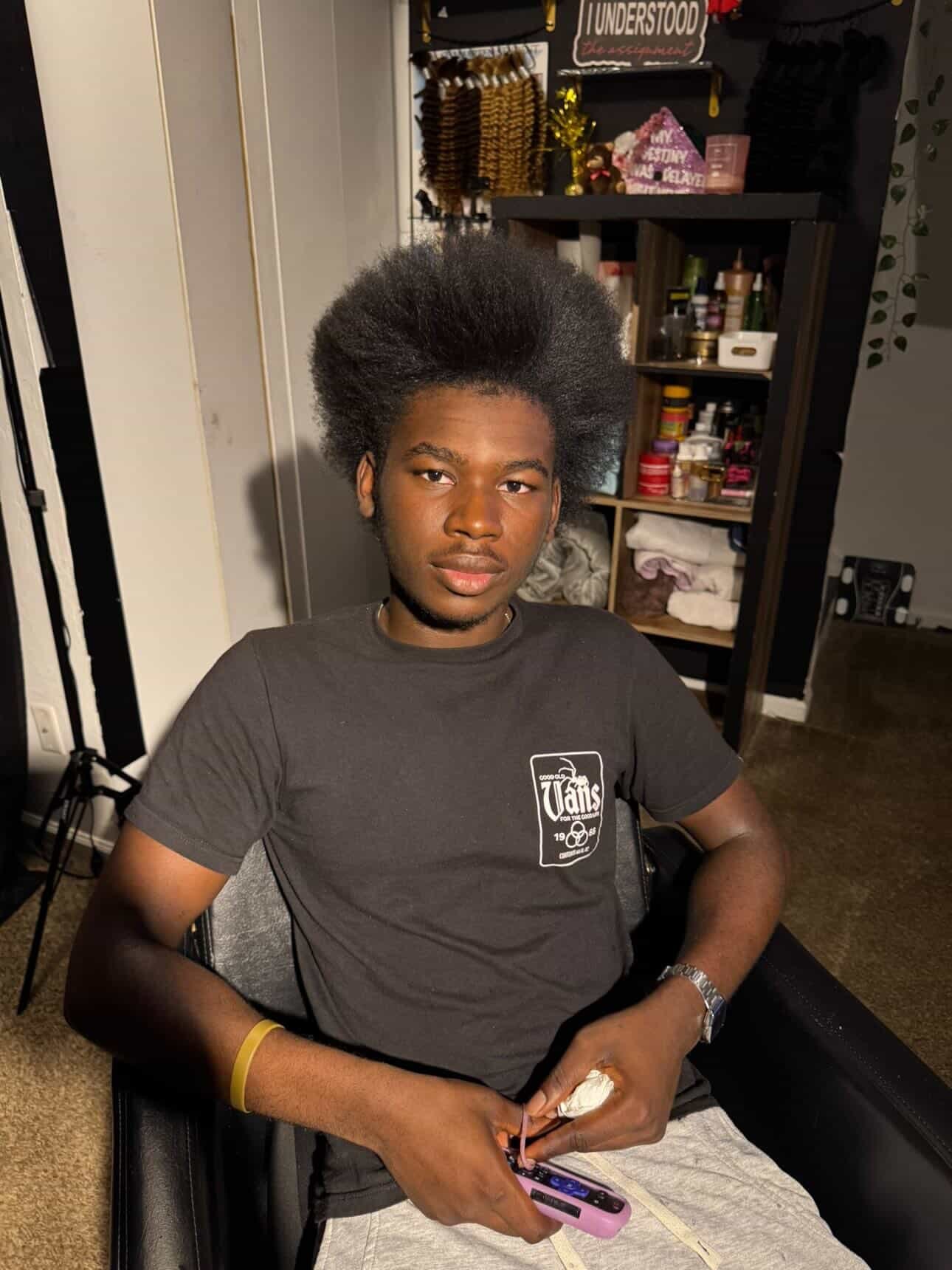Joshua seated with a full hair blowout in warm indoor light