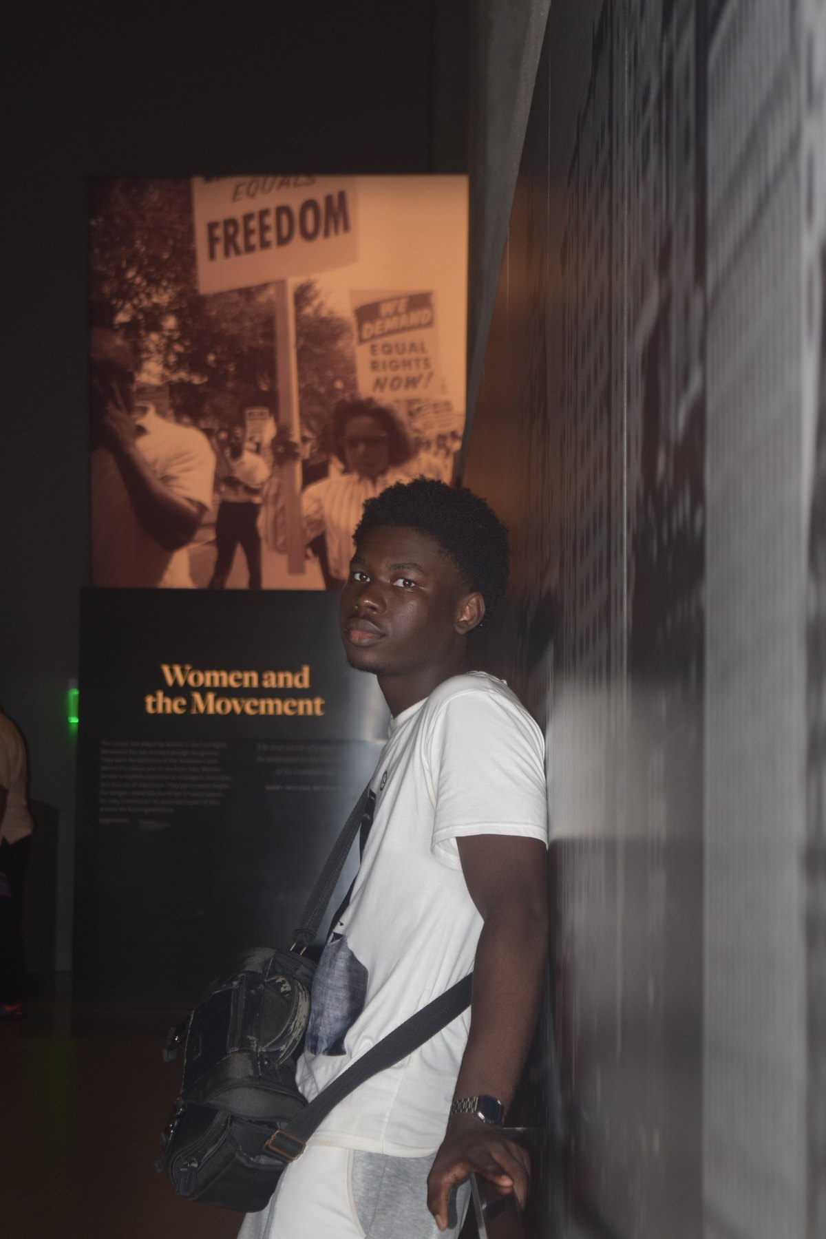 Joshua standing beside a Women and the Movement exhibit